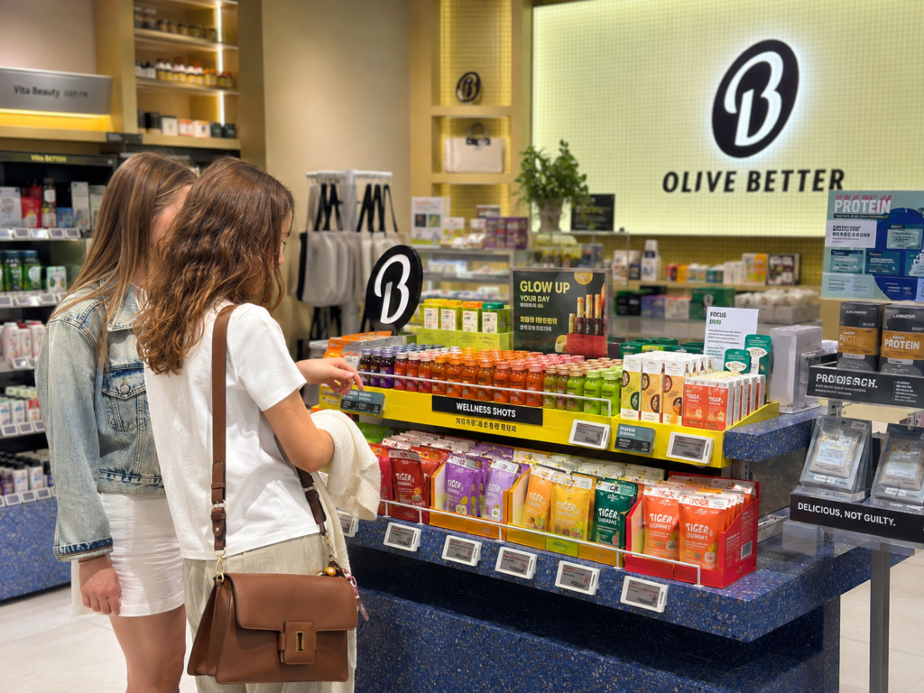 Foreign visitors browsing wellness shots and gummies at Olive Better in Korea