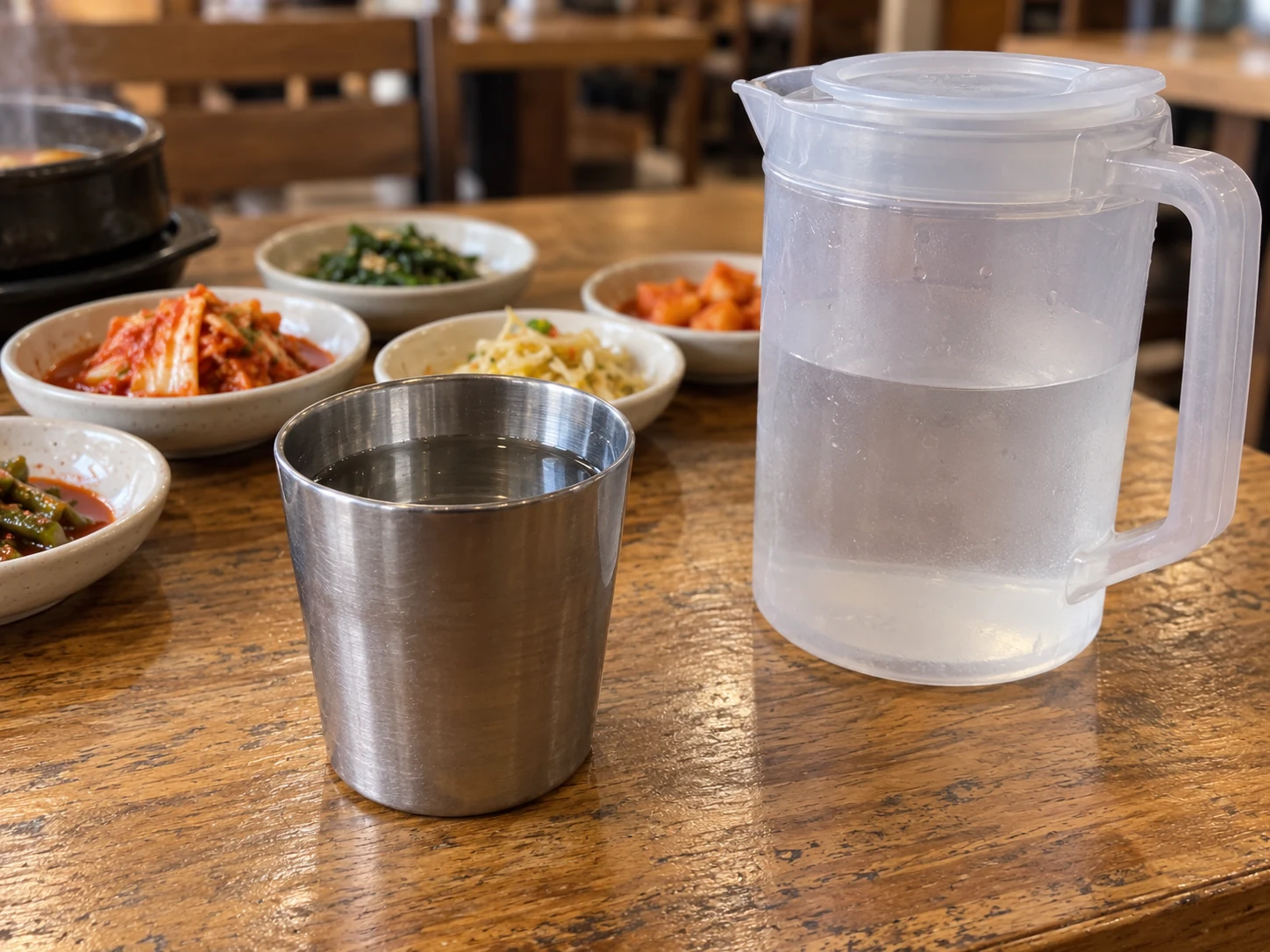 A steel water cup and reusable water jug on a Korean restaurant table.